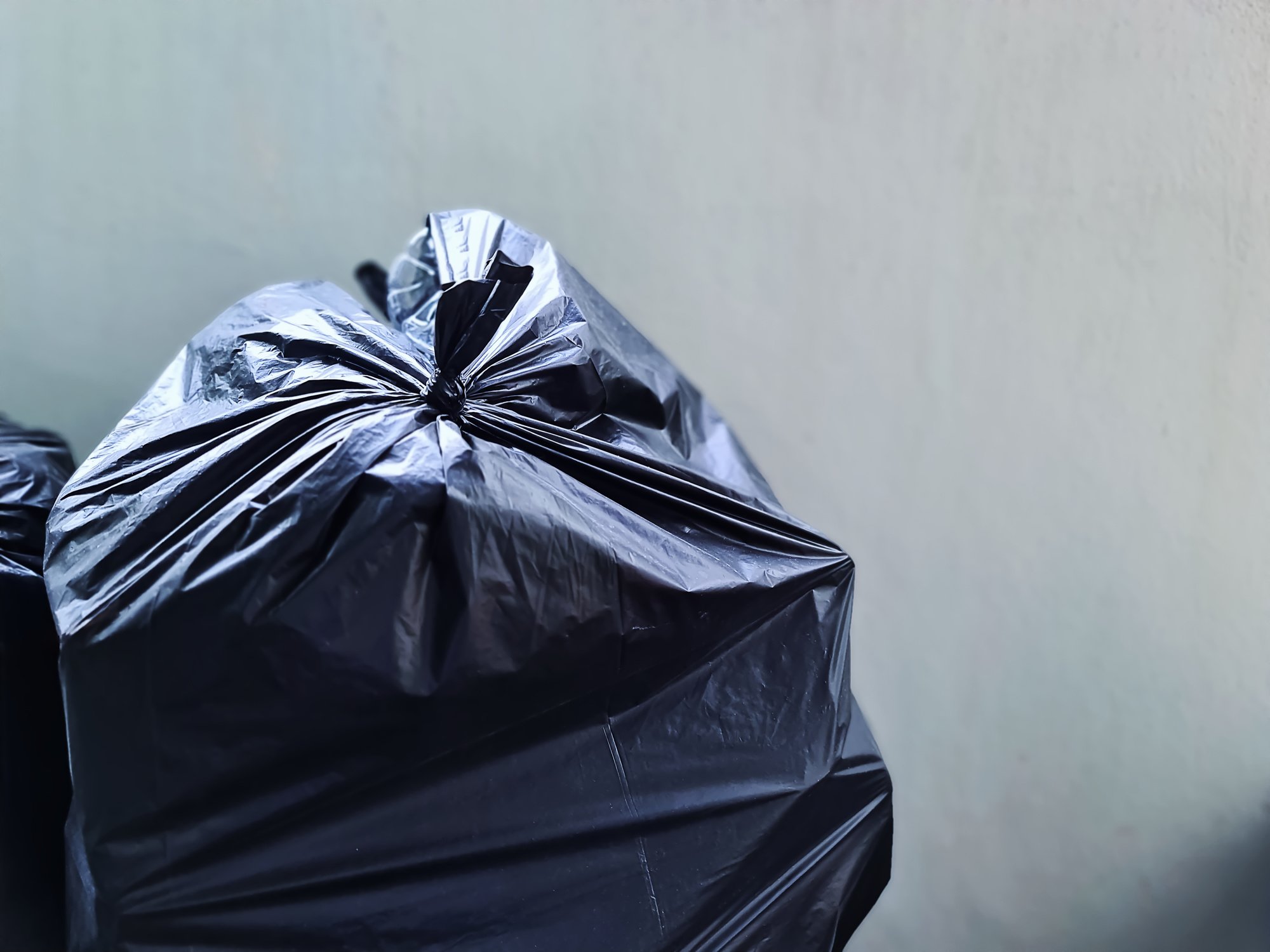 Black Plastic Bag Near Concrete Wall